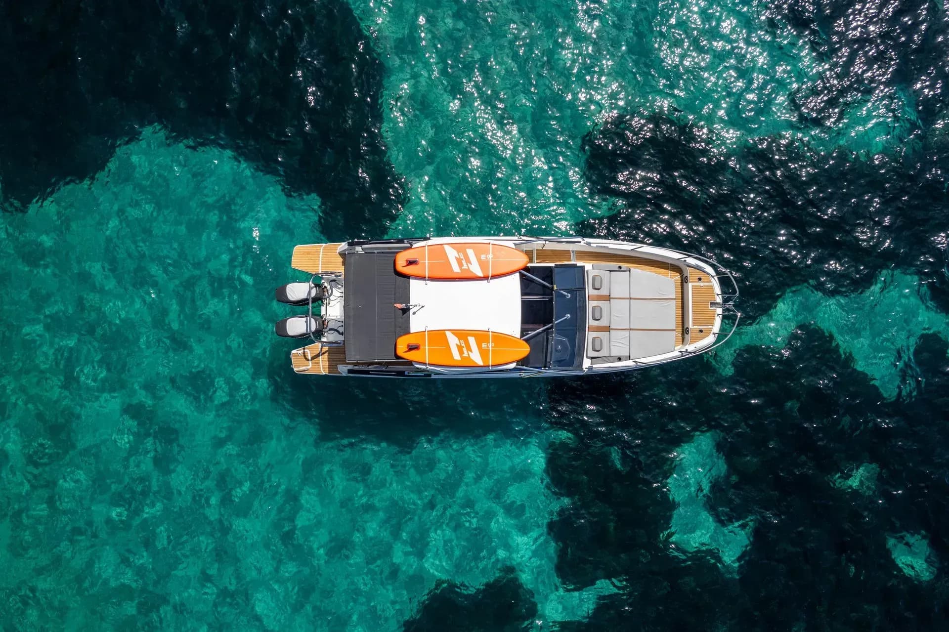 Top view of boat with paddleboards in turquoise water